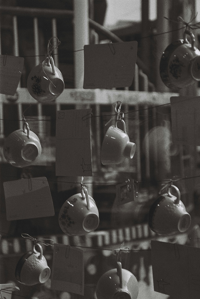 A collection of teacups hung on twine with little notes (black & white)